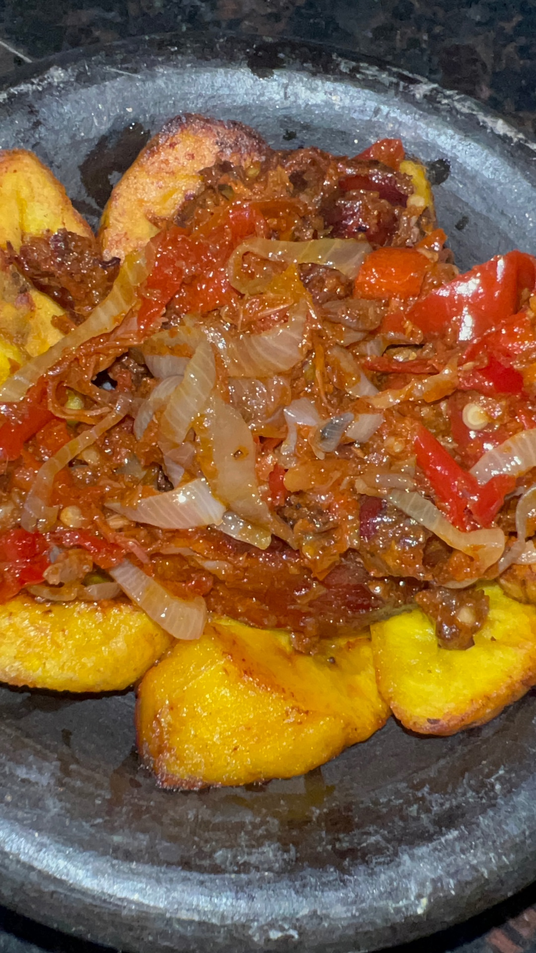 Grilled fish served with fried plantain and pepper sauce in an earthenware bowl
