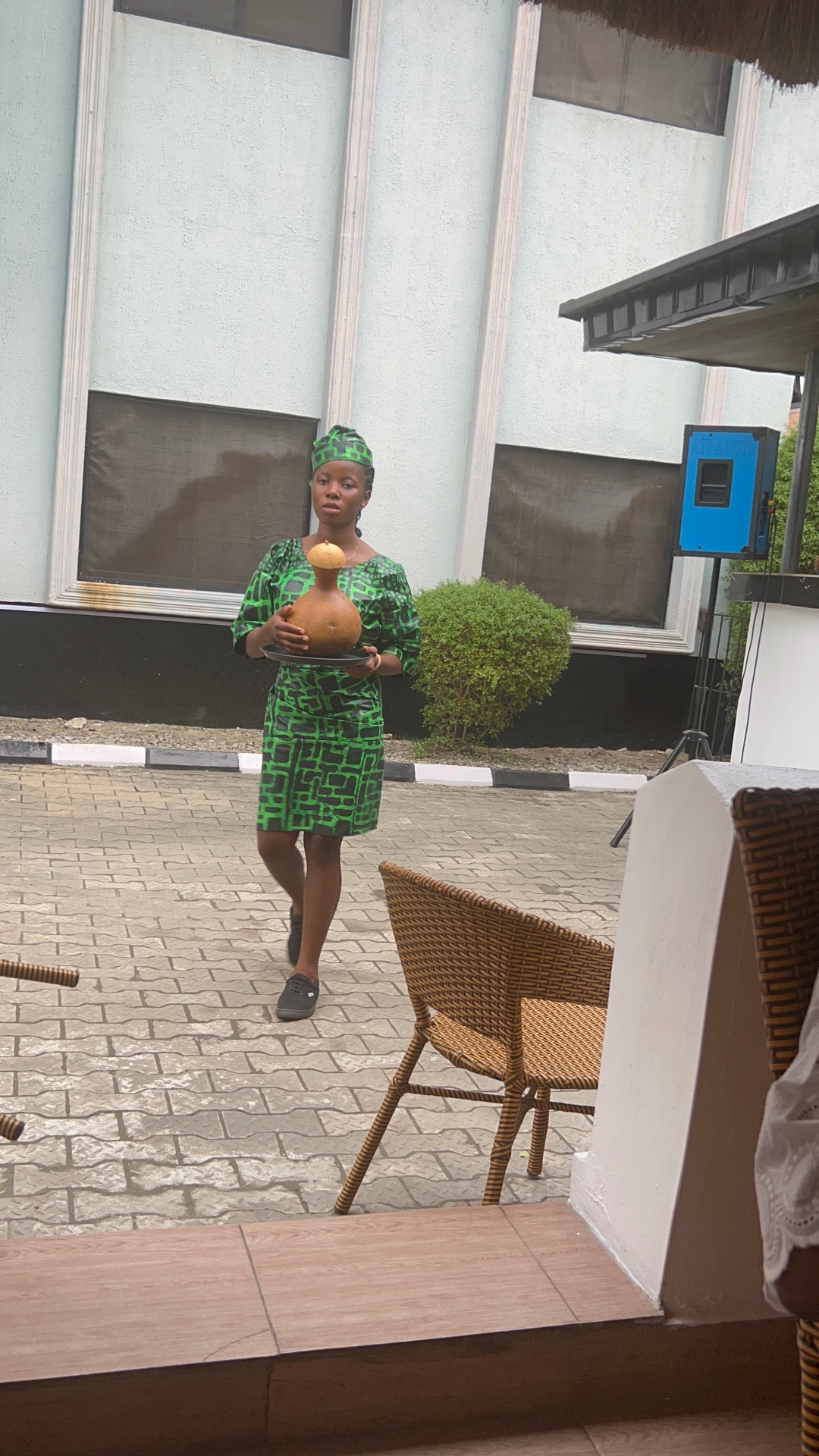 Server carrying a calabash gourd across the courtyard