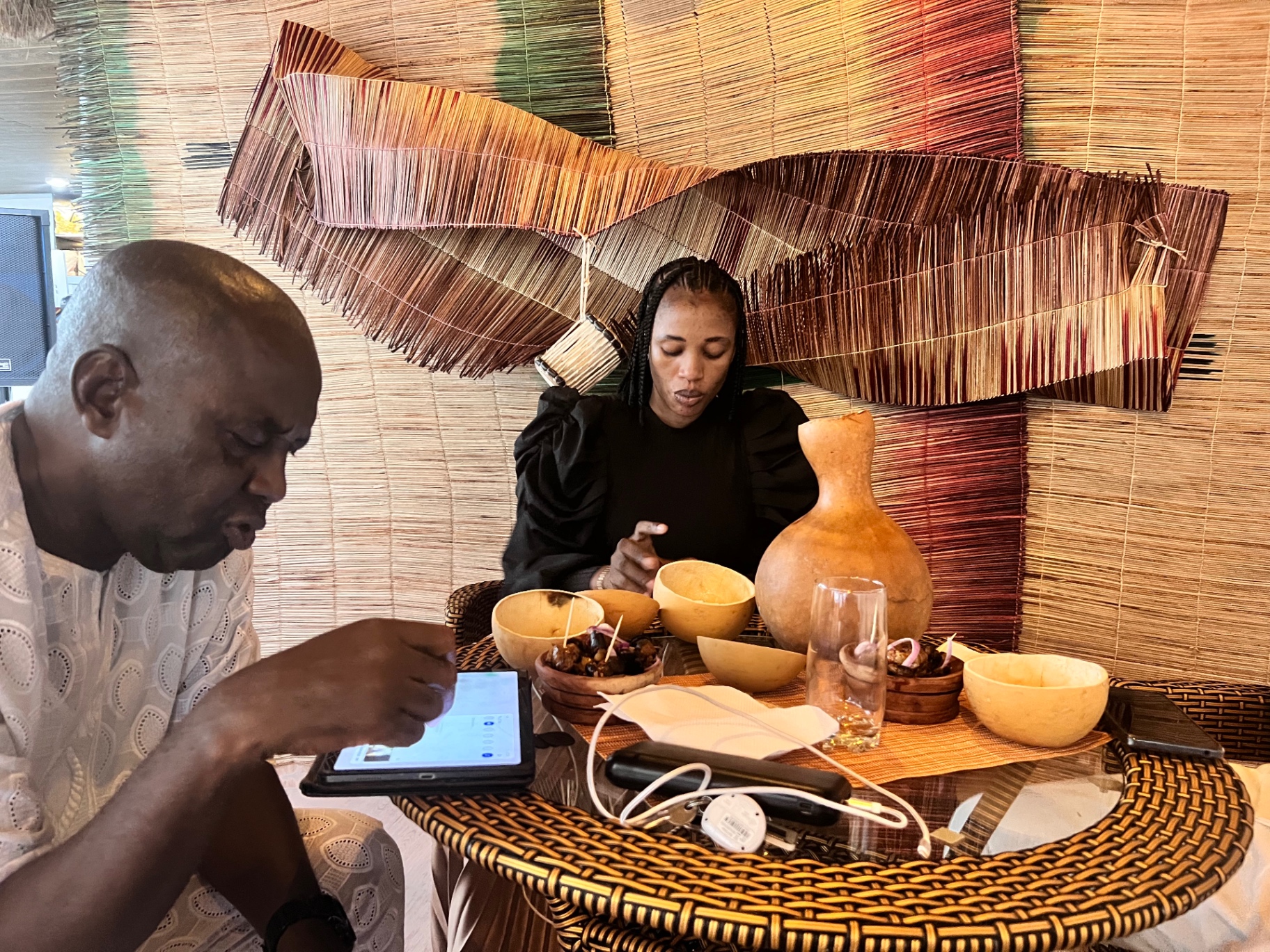 Guests drinking palm wine at cane tables under the thatched roof